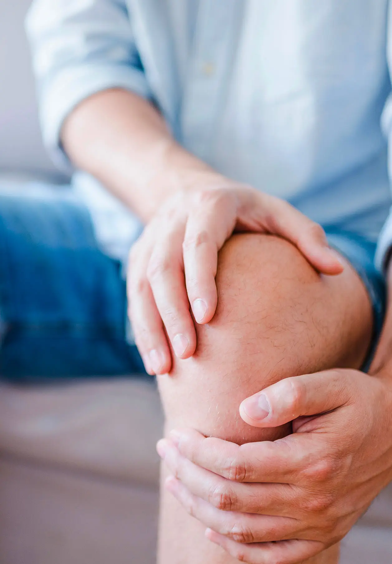 A man holding his knee in pain due to arthritis